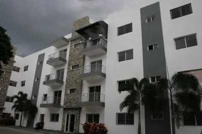 a large white building with balconies and palm trees at Residencial Vista Del Bosque in Santiago de los Caballeros