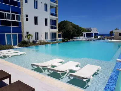 a large swimming pool with lounge chairs and a building at Susy paradise in Sosúa