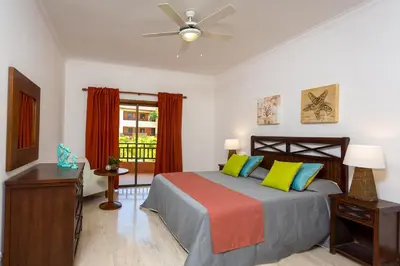 a bedroom with a bed and a dresser and a window at Tot Punta Cana Apartments in Punta Cana