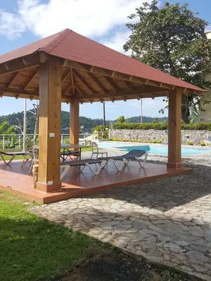 a wooden pavilion with a picnic table next to a pool at Hidden Paradise at Apto Del Cerro in Santa Bárbara de Samaná