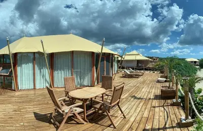a wooden deck with a table and chairs and a tent at Eco Del Mar in Pedernales