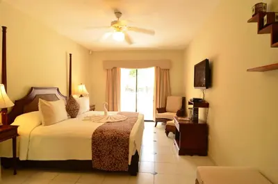 a hotel room with a bed and a chair at Cofresi Palm Beach & Spa Resort - All Inclusive in San Felipe de Puerto Plata