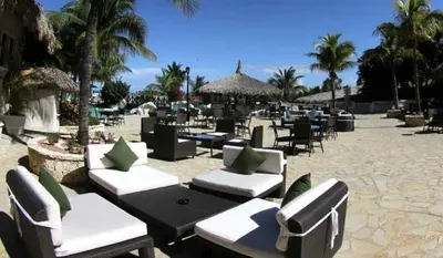 a resort patio with chairs and tables and palm trees at Cofresi Palm Beach & Spa Resort - All Inclusive in San Felipe de Puerto Plata