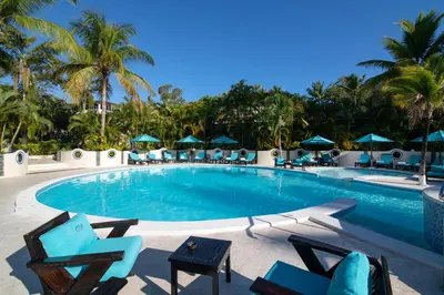 a swimming pool with chairs and palm trees at Lifestyle Crown Residence Suites in San Felipe de Puerto Plata