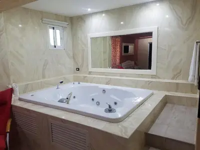 a large white tub in a bathroom with a mirror at Kitewind Apartamentos Cabarete in Cabarete