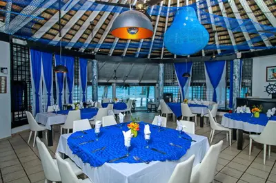 a banquet hall with blue tables and white chairs at Kitewind Apartamentos Cabarete in Cabarete