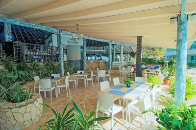 a restaurant with tables and white chairs and plants at Kitewind Apartamentos Cabarete in Cabarete