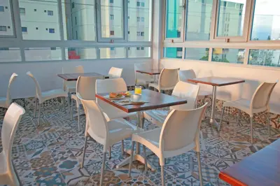 a restaurant with tables and chairs and windows at Palmetto Hotel in Santiago de los Caballeros