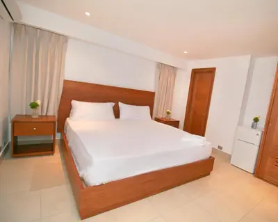 a bedroom with a large bed with white sheets at Palmetto Hotel in Santiago de los Caballeros