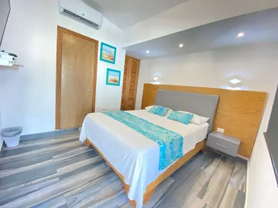 a bedroom with a bed and a wooden floor at Hotel Agua Dulce in Boca Chica