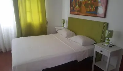 a bedroom with a white bed with a green headboard at Hispaniola Residencial private villas in Sosúa