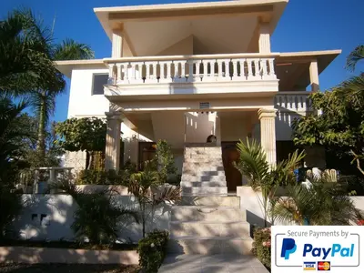 a white house with palm trees in front of it at Caleton Group in Río San Juan