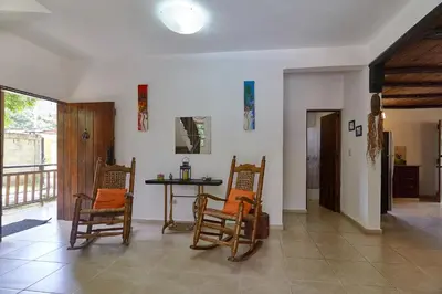 a living room with chairs and a table and a window at Villa Bayacanes con piscinas privadas in Jarabacoa