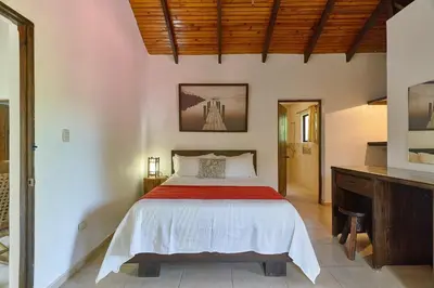 a bedroom with a bed with a red and white blanket at Villa Bayacanes con piscinas privadas in Jarabacoa