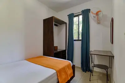 a bedroom with a bed and a desk and a window at Villa Bayacanes con piscinas privadas in Jarabacoa