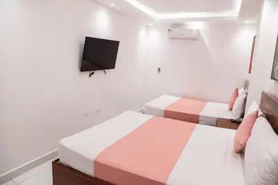 a bedroom with two beds and a tv on the wall at Cataleya Hotel in Santo Domingo