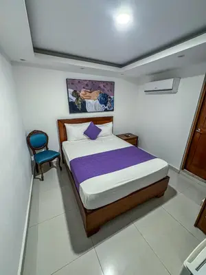 a bedroom with a bed and a blue chair at Cataleya Hotel in Santo Domingo