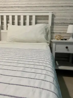 a white bed with a striped blanket and a nightstand at B&B Villa Luna in Bayahibe