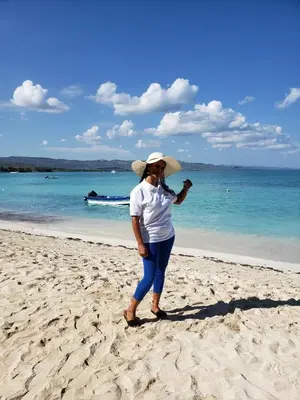 a woman wearing a hat standing on a beach at La Ensenada Boutique Hotel in Punta Rucia