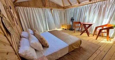 a bedroom with a bed in a room with a table at Glamping EcoLodge Cueva De Las Aguilas in Pedernales