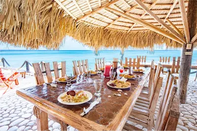 a table with plates of food on a beach at Glamping EcoLodge Cueva De Las Aguilas in Pedernales