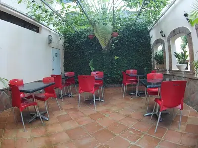 a patio with red chairs and tables and a hedge at Hotel Maison Gautreaux in Santo Domingo