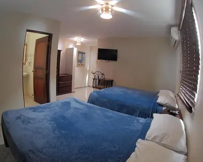 a hotel room with two beds and a television at Hotel Maison Gautreaux in Santo Domingo