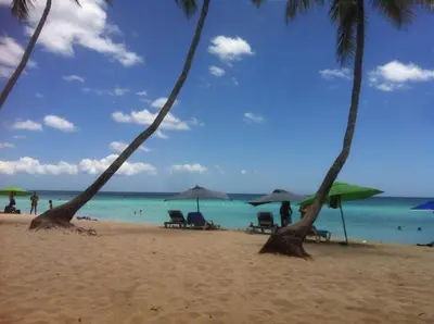 a beach with chairs and umbrellas and the ocean at Casita Blanca Bayahibe in Bayahibe