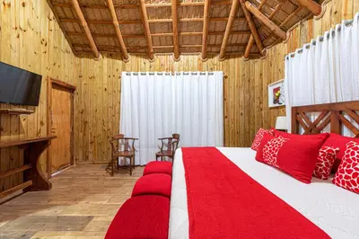 a bedroom with a bed with red pillows and a television at Vista de Águilas Ecolodge in Pedernales