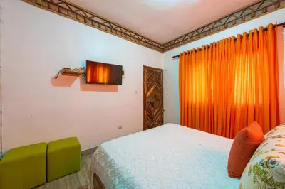 a bedroom with a bed and an orange curtain at Vista de Águilas Ecolodge in Pedernales