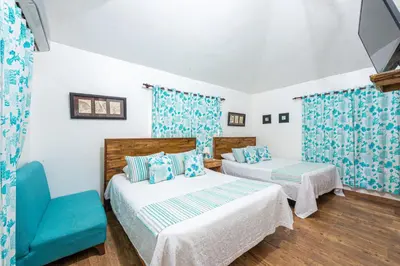 a bedroom with two beds and a blue chair at Vista de Águilas Ecolodge in Pedernales