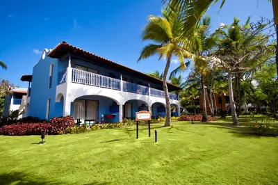 a building with palm trees and a sign in the yard at Catalonia Bayahibe - All Inclusive in Bayahibe