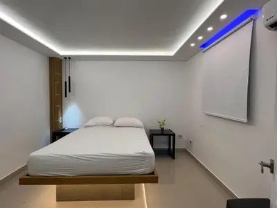 a bedroom with a white bed and a projection screen at Alegria Hostal in Santiago de los Caballeros