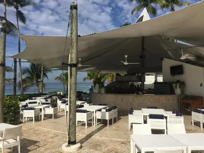 a restaurant with white tables and chairs and the ocean at Marbella Juan Dolio in Juan Dolio