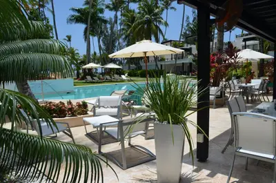 a patio with tables and chairs and a swimming pool at Aligio Beachfront Paradise in Las Terrenas