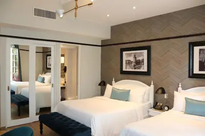 a hotel room with two beds and a mirror at Hotel Conde de Penalba in Santo Domingo