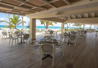 a restaurant on the beach with tables and chairs at Emotions by Hodelpa Puerto Plata in San Felipe de Puerto Plata