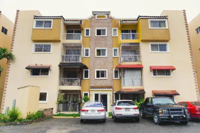 two cars parked in a parking lot in front of a building at Apartamento Los Rieles in Santiago de los Caballeros
