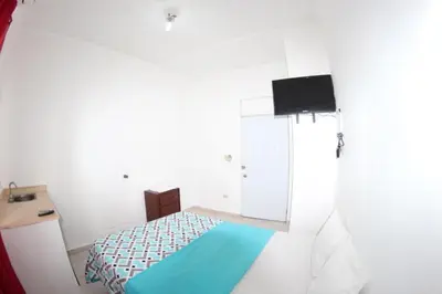 a white room with a bed and a tv at Caribbean Hotel Santo Domingo in Santo Domingo