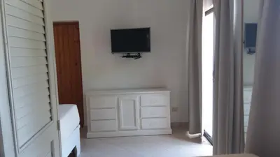 a room with a television on a wall with a dresser at Hotel Zapata in Boca Chica