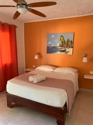 a bedroom with a bed with an orange wall at Hotel Pedernales Italia Republica Dominicana in Pedernales