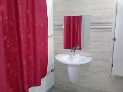 a bathroom with a red shower curtain and a sink at Hostel Quintonido in Jarabacoa