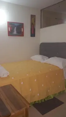 a bedroom with a bed with a yellow sheet on it at Hostel Quintonido in Jarabacoa