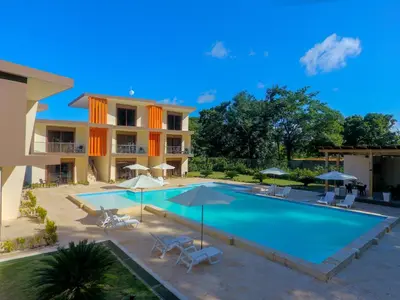 a swimming pool with chairs and umbrellas next to a building at Caribbean Diamond Boutique Hotel in Sosúa