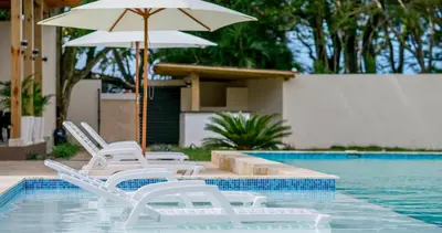 a group of chairs and an umbrella next to a swimming pool at Caribbean Diamond Boutique Hotel in Sosúa