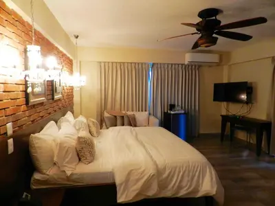 a bedroom with a white bed with a ceiling fan at MON Hotel Boutique in Constanza