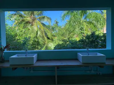 two sinks in a room with a window with palm trees at Aventura Rincon Ecolodge in Las Galeras