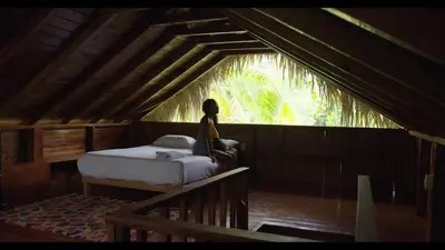 a woman sitting on a bed in a room with a window at Aventura Rincon Ecolodge in Las Galeras