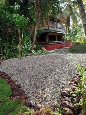 a house with a balcony on top of a gravel driveway at Aventura Rincon Ecolodge in Las Galeras