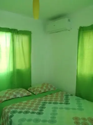 a bedroom with two beds and green curtains at Casa Vasquez in San Felipe de Puerto Plata